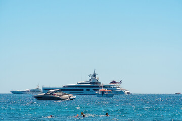 View from the shore, the bay with ships and boats. Luxury premium yacht, takes off landing aircraft, helicopter. Water transport. Rest and vacation in the ocean. Beach.
