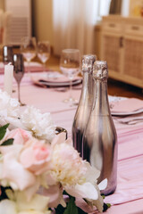 Wedding flowers on the banquet table. Table decoration. Table setting and decorations. Two bottles of champagne.