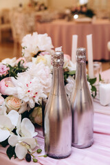 Wedding flowers on the banquet table. Table decoration. Table setting and decorations. Two bottles of champagne.