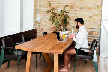 bearded african american man in shirt and underwear sitting near laptop and gesturing while having video call