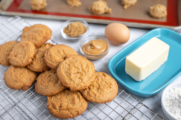 Peanut butter cookies cooling on a rack, with baking ingredients in the background