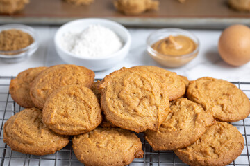 Batch of cookies cooling on a rack, with baking ingredients in the background
