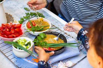 Family eat vegan healthy balanced food on lunch together. Cooked lentil, vegetables salads.