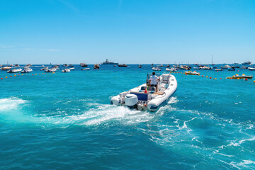 Naklejka premium A small watercraft begins to move. Light motor boat. Inflatable boards. Sunny summer day. The concept of renting a ship and touristic excursions. Fishing and movement.