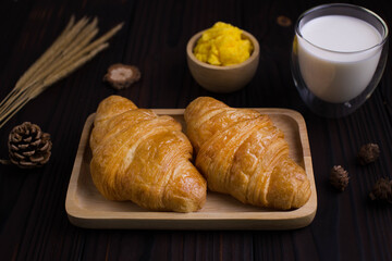 Freshly croissants breakfast with milk and butter on wooden background 