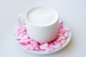 Cappuccino cup decorated with pink hearts and marshmallows on white background