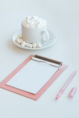 Cappuccino with marshmallows and tablet folder on white background