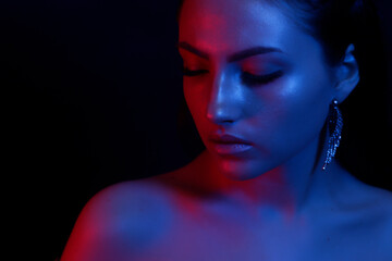 Fototapeta premium The young girl closeup in bright neon light. Fashionable high lighter makeup. The concept of the trend image and neon light.