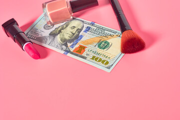 Various cosmetics accessories and banknote of 100 dollars on pink background. Concept of cost of beauty