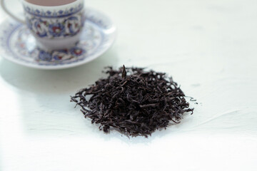 dry black tea and mug with tea. some sort of dried tea in studio, with white cup and tea pot