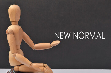 Wooden figure with text "NEW NORMAL" on black background.