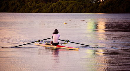 A woman takes an early morning workout rowing on a river. © JAMES