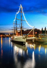 Old sail boat at the harbor, with city lights and water reflections, at twilight. Puerto Madero, Buenos Aires, Argentina 