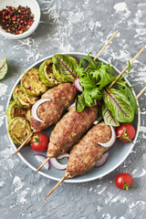 Grilled Lula kebab lamb with onions, salad, tomato and zucchini on plate. Asian traditional meat dish	
