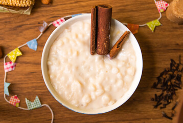 Canjica, Mungunza or Munguza with cinnamon, Typical in Festa Junina Celebration. Traditional food of Brazil, June Party sweet. Wood Background.