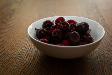 Bowl of fresh cherries on wooden table