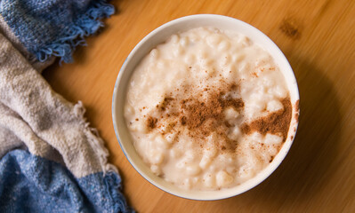 Canjica, Mungunza or Munguza with cinnamon, Typical in Festa Junina Celebration. Traditional food of Brazil, June Party sweet. Wood Background.