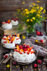 Delicious Pavlova meringue cake decorated with fresh berries on rustic background