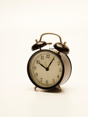 Black alarm clock on white background.