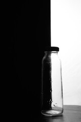 A small bottle on a black and white background. Half black and half white
