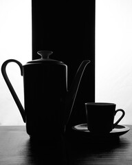 concept kettle and cups with saucer on a black white background