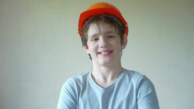 portrait of a funny cheerful boy in a construction helmet