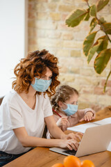 selective focus of curly freelancer mother in medical mask using laptop near daughter at home