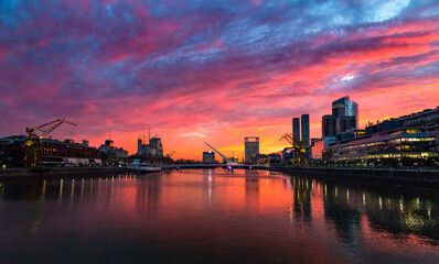 Puerto Madero Bridge and city by the river, during sunrise, with colorful clouds. 