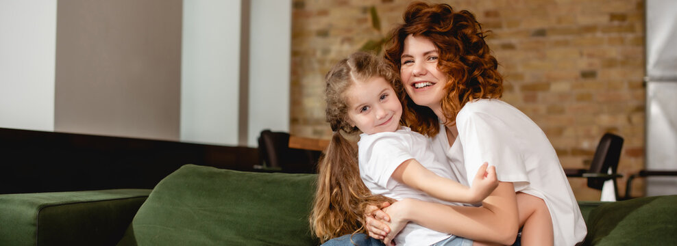 horizontal image of cute daughter hugging happy and curly mother copy space