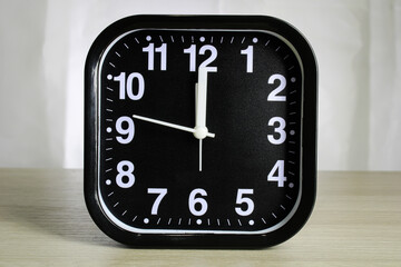 Black alarm clock with white arrows and numbers.
