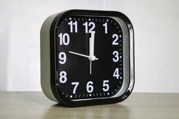 Black alarm clock with white arrows and numbers.