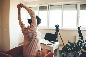 Fototapeta premium Caucasian teacher ready for the online lessons at the computer with a book and modern camera in front