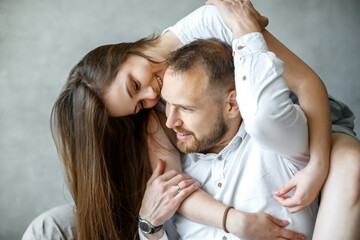 A young family is sitting at home and cuddling. Happy couple.On a gray background. Close-up portrait