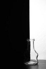 A small bottle on a black and white background. Half black and half white