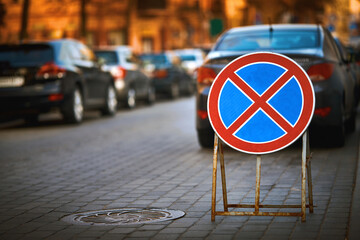 No parking, road sign standing on the road. Parking violations, cars stand on the road with traffic...
