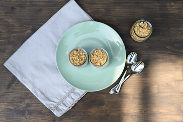 Two small jars with yogurt and chia seeds, granola on a plate. Selective focus.