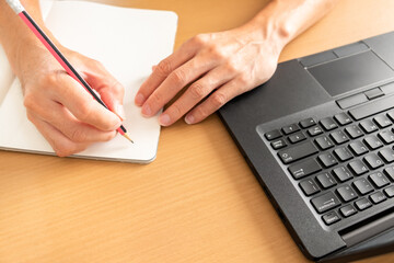 laptop, notebook on the wooden table. hands of businessman typing laptop keyboard at afternoon. a adult man in casual clothing is working on the chair for work from home.