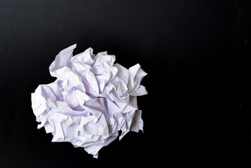 Ball of rumpled white paper on black background