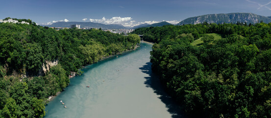 The confluence of two rivers between the banks against the background of mountains and clouds.