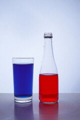 bottle and glass. In which the red and blue liquids are poured on a white background