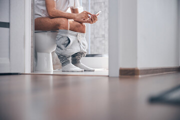 Man using his gadget in the water closet