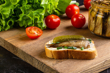 Sandwich with sprots and cucumber, on a board with tomatoes and salad