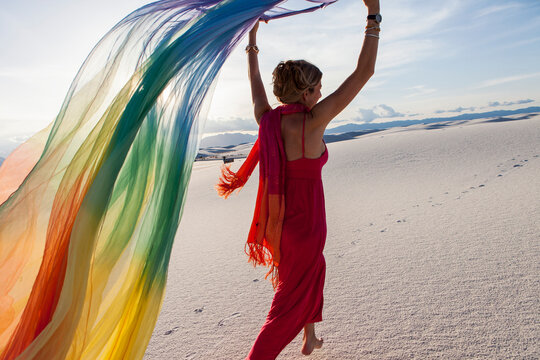 adult woman running with rainbow streamer in sand dunes, White Sands Nat'l Monument