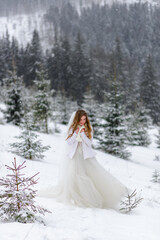 Fototapeta na wymiar Beautiful bride rejoices in the snow. Winter wedding in the mountains.
