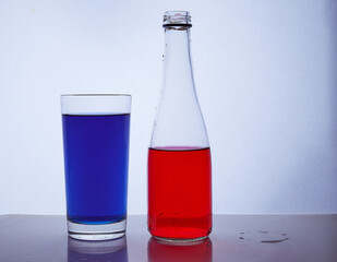 bottle and glass. In which the red and blue liquids are poured on a white background