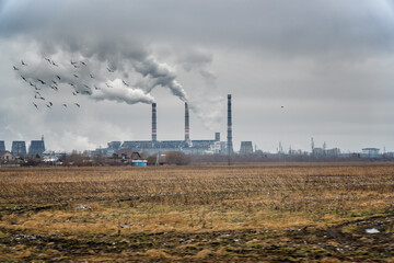 Fototapeta na wymiar View of a chemical plant with Smoking chimneys against a dark cloudy dirty sky