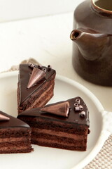 Chocolate cake slice with curl on white background. cake with whipped cream and mascarpone filling. Delicious naked cake filled with cream, topped with chocolate and decorated with flowers,