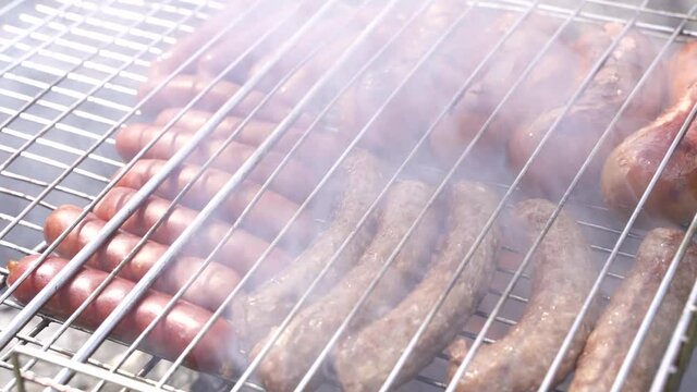 sausages and cevapcici fried meat grilled on an iron grate .
