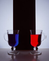 silhouettes of two glasses on a black and white background. Blue and red liquid