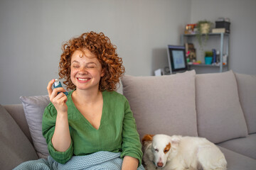 Woman with asthma inhaler in light room. Pretty woman taking her inhaler at home at the living room. Young woman using asthma inhaler at home. Woman using inhaler during asthmatic attack at home
